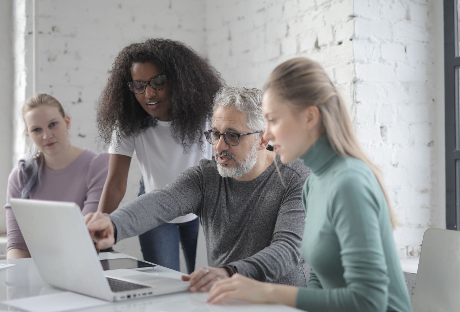 Quatro pessoas reunidas em volta de um notebook, uma delas apontando para a tela